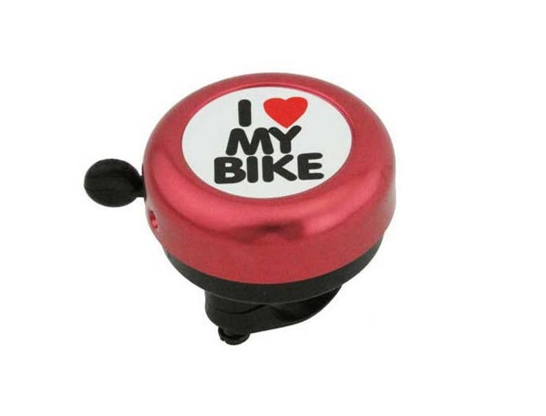 May include: A red bicycle bell with the text "I ❤️ MY BIKE" in black letters and a red heart on a white background. The bell has a black lever and a black base, designed to attach to a bicycle handlebar.