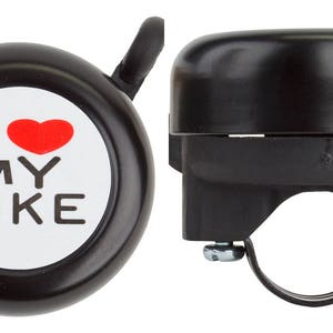 May include: Black bicycle bell with the text "I ❤️ MY BIKE" in white and red. The bell has a rounded top and a mounting bracket for attachment to the handlebars. A small lever is attached to the top for ringing.