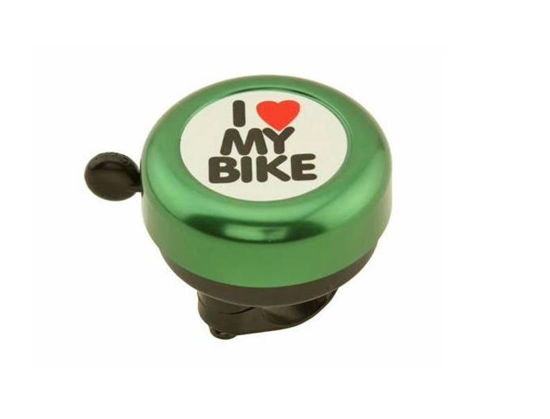 May include: A green bicycle bell with the text "I ❤️ MY BIKE" in black letters and a red heart on a white background. The bell has a black lever and base, designed to attach to a bicycle handlebar.