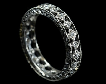 Könnte beinhalten: Ein silberner Bandring mit einem filigranen, komplizierten Design, das mit kleinen Diamanten besetzt ist, die in einem sich wiederholenden Muster angeordnet sind.