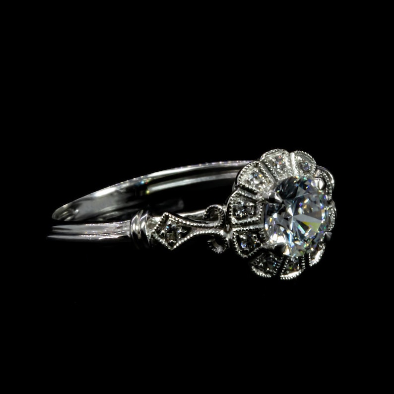 K&ouml;nnte beinhalten: Ein silberner Ring mit einem gro&szlig;en, runden, klaren Diamanten, der in einem floralen Design gefasst ist.