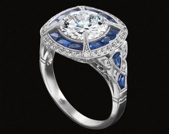 May include: A silver ring with a large, round, clear diamond surrounded by a halo of smaller diamonds and blue sapphires.