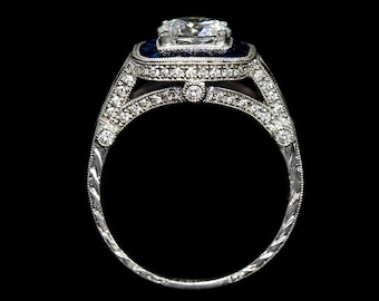 May include: A silver engagement ring with a large, clear, square-cut diamond surrounded by a halo of smaller diamonds. The ring band is decorated with a delicate, engraved pattern and features a blue sapphire accent.