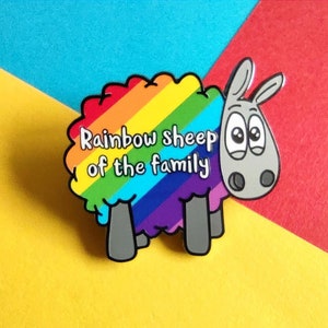 May include: A rainbow sheep pin with the text "Rainbow sheep of the family" on the wool. The sheep has a grey face with big eyes and a surprised expression.
