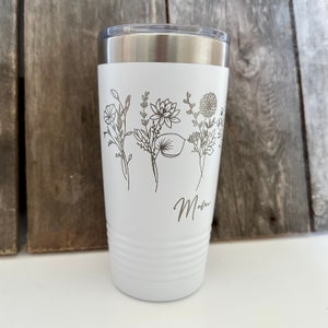 May include: White stainless steel tumbler with a floral design and the word "Mom" engraved on the side.