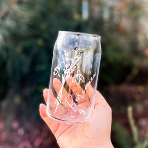 May include: A clear glass can with a floral design and the name "Berenice" etched on the side.