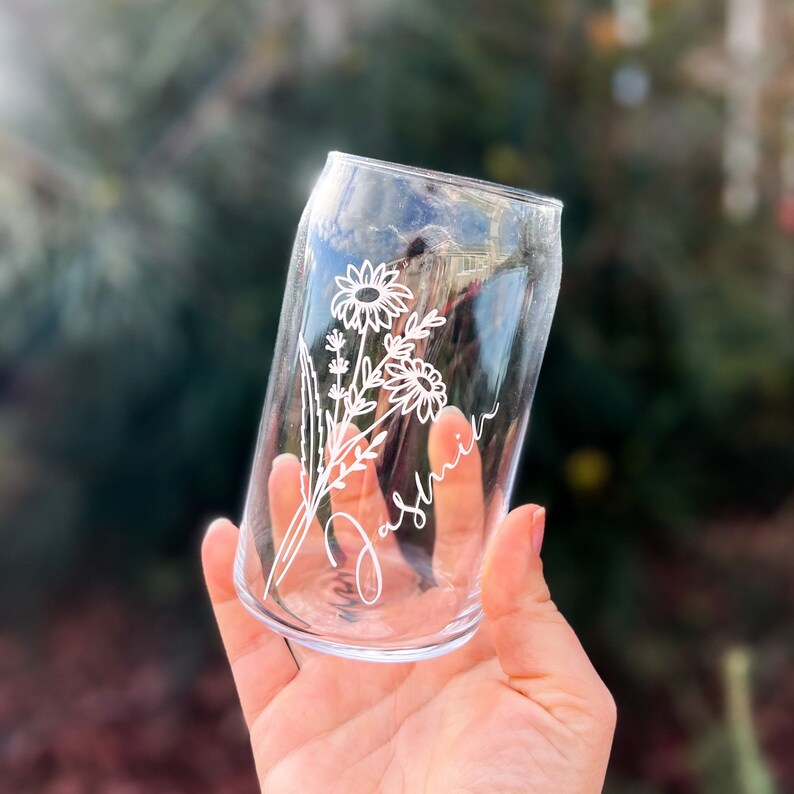 May include: A clear glass can with a white floral design and the name "Jasmine" etched on the side.