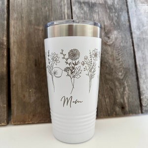 May include: White stainless steel tumbler with a floral design and the word "Mom" engraved on the side.