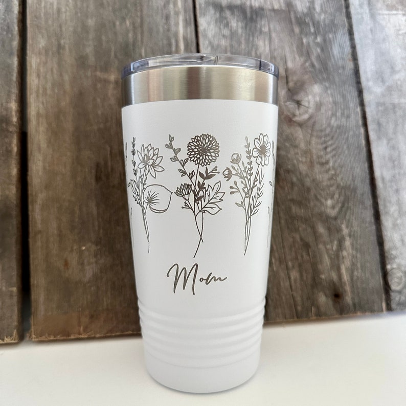 May include: White stainless steel tumbler with a floral design and the word "Mom" engraved on the side.