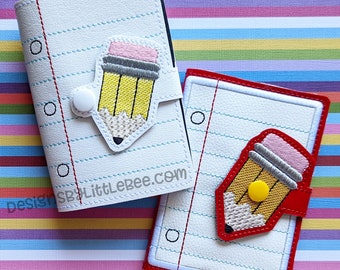 May include: Two white notebook covers with red and yellow pencil designs. The covers have a lined paper design and a button closure. The text "designsbylittlebee.com" is on the left cover.