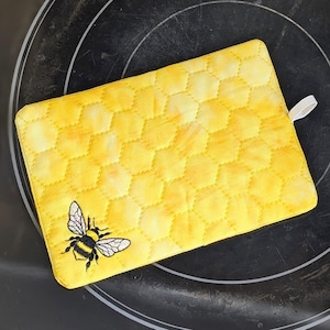 Puede incluir: Manopla de cocina amarilla acolchada con un patrón de panal y un diseño de abeja bordado.