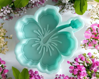 May include: A teal blue silicone mold shaped like a hibiscus flower. The mold is designed for making decorative crafts.