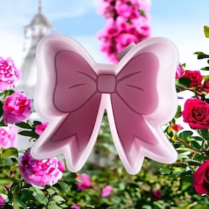 May include: A pink silicone mold shaped like a bow. The mold is designed for making resin crafts.