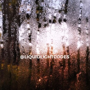 May include: A close-up of a window with condensation on the glass. The condensation forms small droplets of water, creating a blurry effect. The text "@liquidlightcodes" is visible in the center of the image.