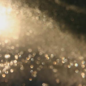 May include: An abstract image with a soft focus effect, featuring a blend of warm, golden tones and a scattering of bokeh lights. The overall effect is a dreamy, ethereal composition, with a gradient from light to dark.