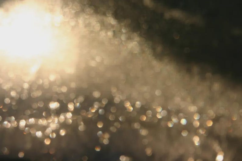 May include: An abstract image with a soft focus effect, featuring a blend of warm, golden tones and a scattering of bokeh lights. The overall effect is a dreamy, ethereal composition, with a gradient from light to dark.
