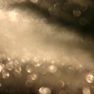 May include: Abstract image with a soft focus effect. The image features a gradient of light and dark tones, with a scattering of out-of-focus, circular highlights. The overall effect is a dreamy, ethereal aesthetic.