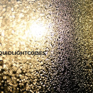 K&ouml;nnte beinhalten: Abstraktes Bild mit Bokeh-Effekt, das einen Farbverlauf von Gold- und dunklen T&ouml;nen aufweist. Das Bild hat einen verschwommenen Hintergrund mit kleinen, kreisf&ouml;rmigen Lichtreflexen. Der Text lautet "@LIQUIDLIGHTCODES".