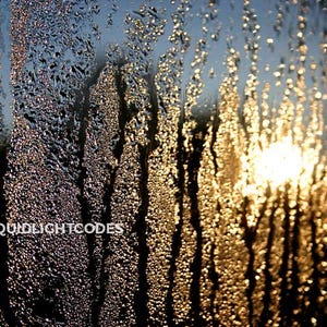 Könnte beinhalten: Nahaufnahme von Wassertropfen auf einer Fensterscheibe, wobei die Sonne durchscheint und einen warmen, goldenen Schein erzeugt. Die Tropfen sind in vertikalen Linien angeordnet und bilden ein strukturiertes, abstraktes Muster.