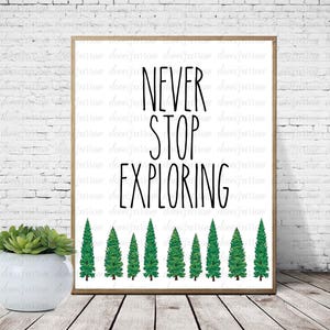 Può includere: Un poster bianco stampabile con testo nero che recita "NEVER STOP EXPLORING". Il poster presenta una fila di pini verdi in basso.