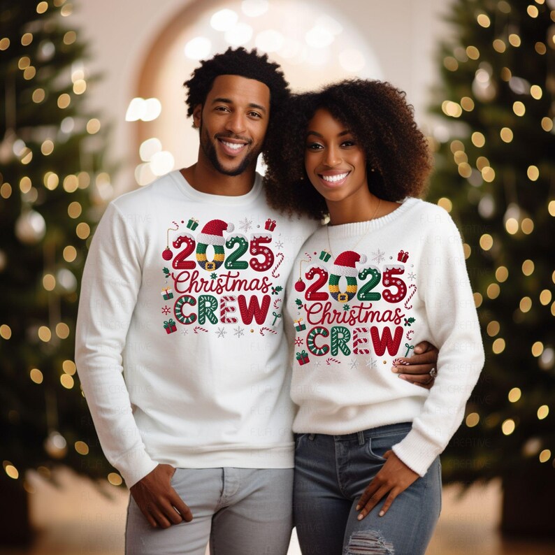 A man and a woman are standing together in front of Christmas trees, both wearing matching white Christmas crew sweaters with the text "2025 Christmas Crew" printed on them.