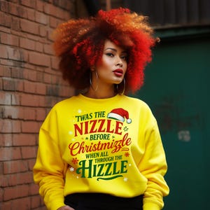 Peut inclure: Un sweat-shirt jaune vif avec le texte "'Twas the Nizzle Before Christmizzle When All Through The Hizzle" en rouge, vert et blanc. Le motif comprend un bonnet de Père Noël et des flocons de neige. La personne porte de grandes créoles et a des cheveux roux et orangés.