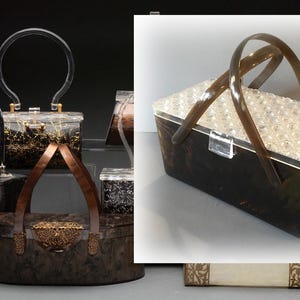 May include: A collection of vintage-style handbags. The bags feature clear, dark, and patterned bodies with various handle designs. One bag has a clear top with a pearl-like texture and dark brown handles.