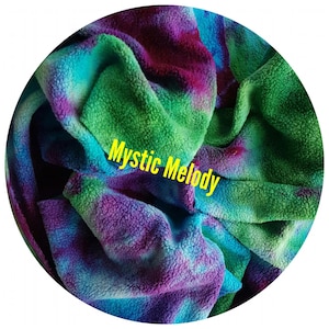 May include: A soft, tie-dye fleece fabric in a circular shape. The cotton sherpa fabric features vibrant colours of green, blue, and purple. The text "Mystic Melody" is displayed in yellow across the organic cotton sherpa fleece fabric. This fabric swatch is an option for custom made organic cotton sherpa gusher pads.