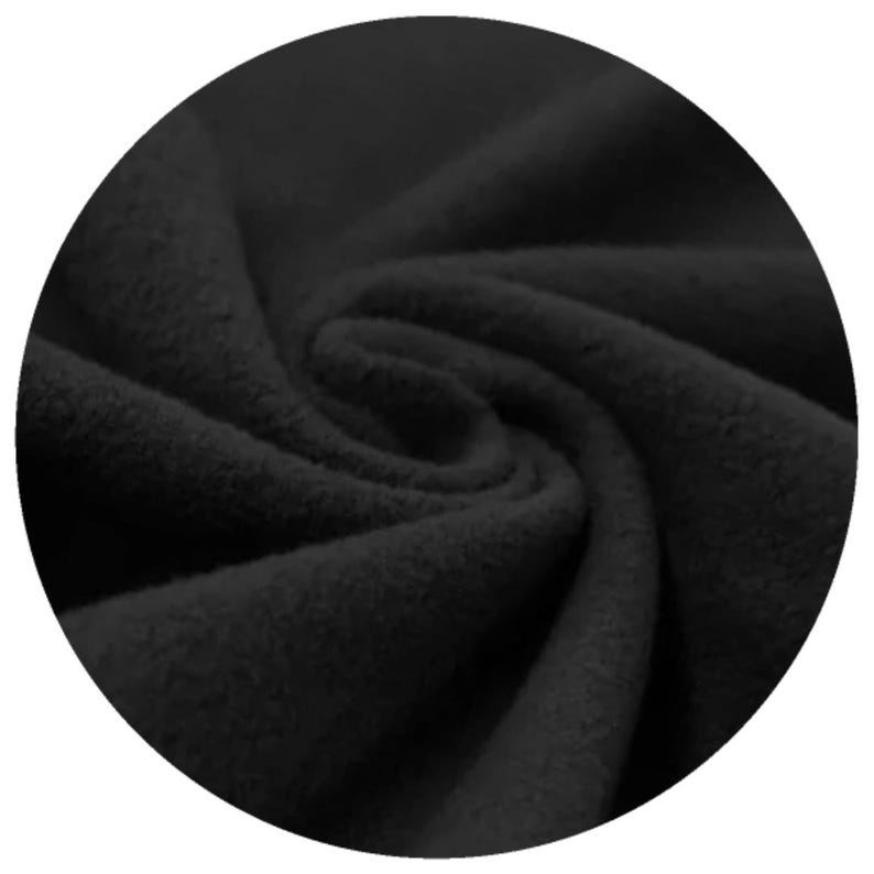Close-up of black organic cotton sherpa fleece fabric, displaying its soft texture and folds. The material appears thick and warm, suitable for clothing or cloth menstrul pads. The image is set against a black background.