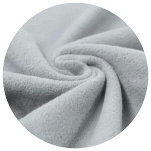 Close-up of SAGE colour organic cotton sherpa fleece fabric, displaying its soft texture and folds. The material appears thick and warm, suitable for clothing or cloth menstrul pads. The image is set against a black background.