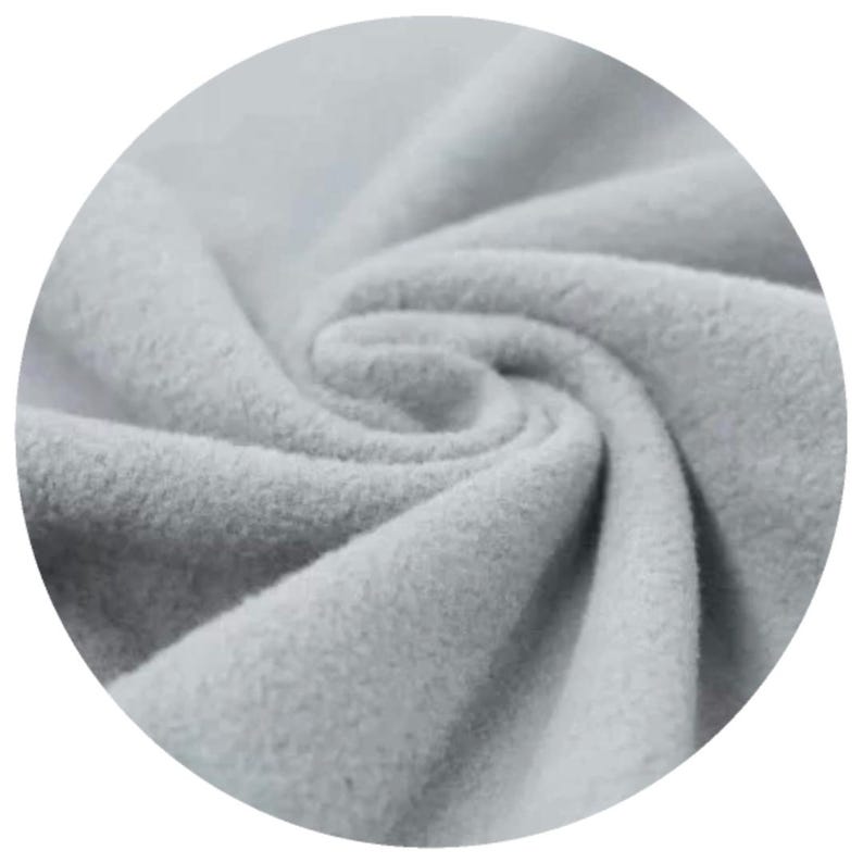 Close-up of SAGE colour organic cotton sherpa fleece fabric, displaying its soft texture and folds. The material appears thick and warm, suitable for clothing or cloth menstrul pads. The image is set against a black background.