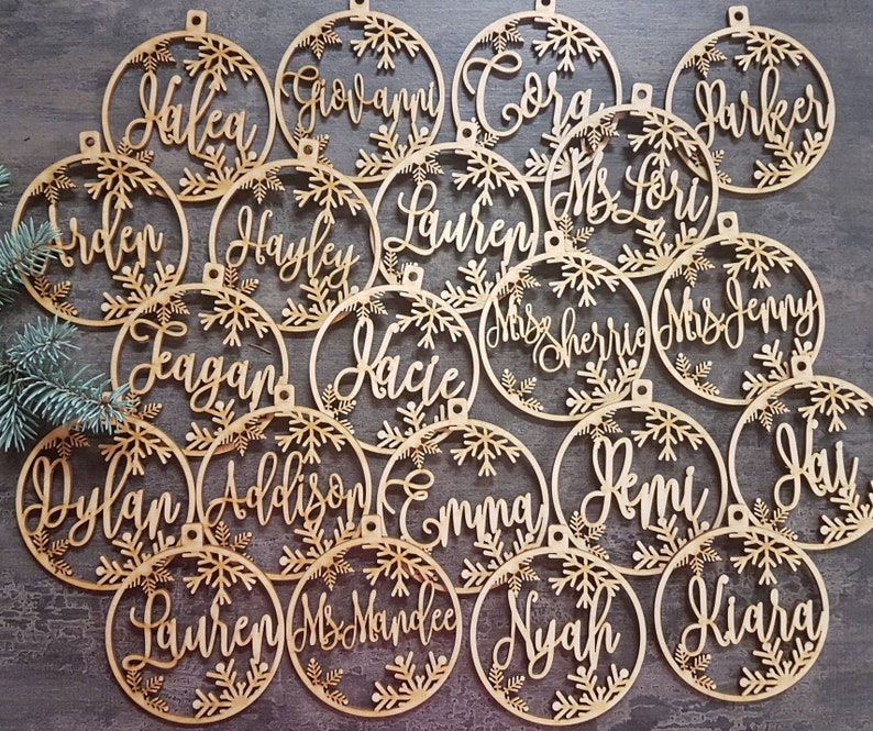 May include: A set of 18 wooden Christmas ornaments with snowflake designs and personalized names, including "Hakea", "Giovanni", "Coral", "Parker", "Erden", "Hayley", "Lauren", "Ms Lori", "Leagan", "Kacie", "Miss Sherrie", "Mrs Jenny", "Dylan", "Addison", "Emma", "Remi", "Hal", "Lauren", "Ms Mandee", "Nyah", and "Kiara".