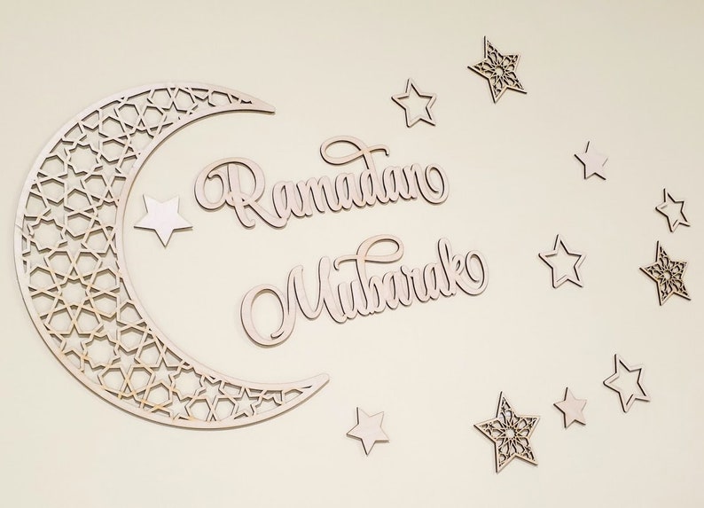 May include: Wooden cutout of a crescent moon with a geometric pattern, the words "Ramadan Mubarak" and several stars.