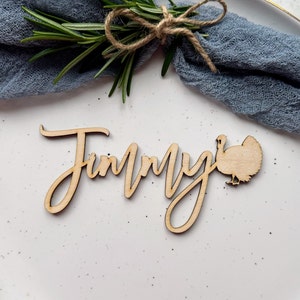 May include: Wooden Thanksgiving place card with the name "Jimmy" written in cursive and a turkey silhouette.