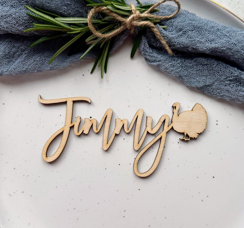 May include: Wooden Thanksgiving place card with the name "Jimmy" written in cursive and a turkey silhouette.
