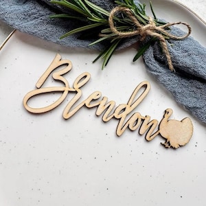 May include: Wooden Thanksgiving place card with the name "Brendan" and a turkey silhouette.