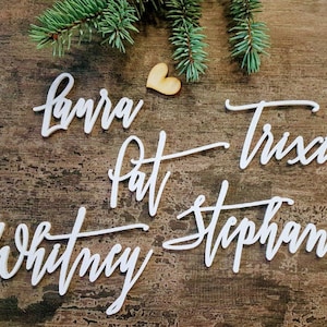 May include: White wooden cutout names, including Laura, Pat, Trisha, and Stephanie, on a rustic wooden background.