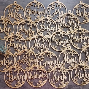 May include: A set of 20 wooden ornaments with snowflake designs and personalized names, including "Halea", "Giovanni", "Cora", "Parker", "Erden", "Hayley", "Lauren", "Mrs. Lori", "Miss Sherrie", "Mrs. Jenny", "Kacie", "Eagan", "Dylan", "Addison", "Emma", "Remi", "Hayl", "Kiara", "Lauren", "Ms. Mandee", and "Nyah".