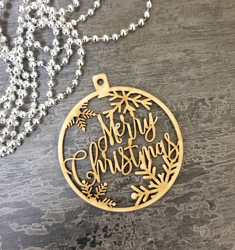 May include: A wooden Christmas ornament in the shape of a circle with the words "Merry Christmas" and snowflakes cut out.