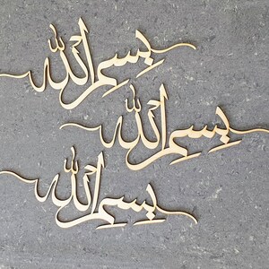 Op de afbeelding: Drie houten uitsnijdingen van de Arabische zin "Insha'Allah" in een cursief schrift. De zin wordt drie keer herhaald, waarbij elke uitsnijding iets kleiner is dan degene erboven.