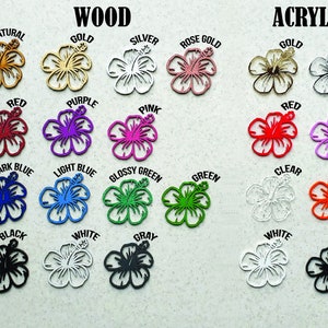 May include: A variety of laser-cut hibiscus flower shapes in wood and acrylic. Colors include natural, gold, silver, red, purple, pink, dark blue, light blue, glossy green, green, black, white, gray, clear, and orange. The word "WOOD" and "ACRYLIC" are at the top.