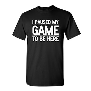May include: Black t-shirt with white text that reads "I paused my game to be here".