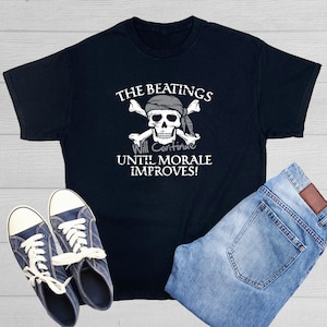 May include: Black t-shirt with a white skull and crossbones graphic. The text "The Beatings Will Continue Until Morale Improves!" is printed below the graphic.