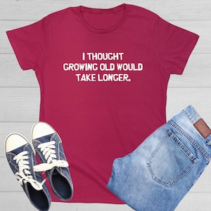 May include: A maroon t-shirt with white text that reads "I thought growing old would take longer."
