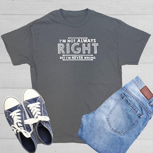 May include: A charcoal gray short-sleeve t-shirt featuring the white text I'M NOT ALWAYS RIGHT BUT I'M NEVER WRONG, paired with a pair of blue denim jeans and a pair of navy blue canvas sneakers with white laces and white rubber soles.