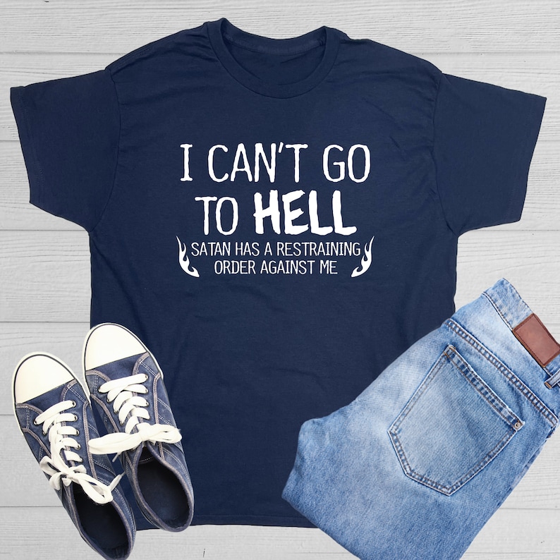May include: A navy blue t-shirt with white text that reads "I can't go to hell Satan has a restraining order against me". The text is surrounded by two flame designs.