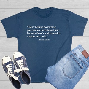 May include: A dark blue t-shirt with a white quote that reads "Don't believe everything you read on the Internet just because there's a picture with a quote next to it."  The quote is attributed to Abraham Lincoln.