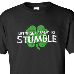 May include: Black t-shirt with a green four-leaf clover and the text "Let's get ready to stumble".