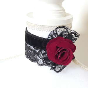 May include: A black velvet choker with black lace trim and a large, red fabric rose.