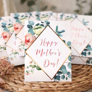 May include: Mother's Day greeting cards with floral designs. Each card features a diamond-shaped frame with the text "Happy Mother's Day!" in pink script. The cards are decorated with watercolor roses and eucalyptus leaves.